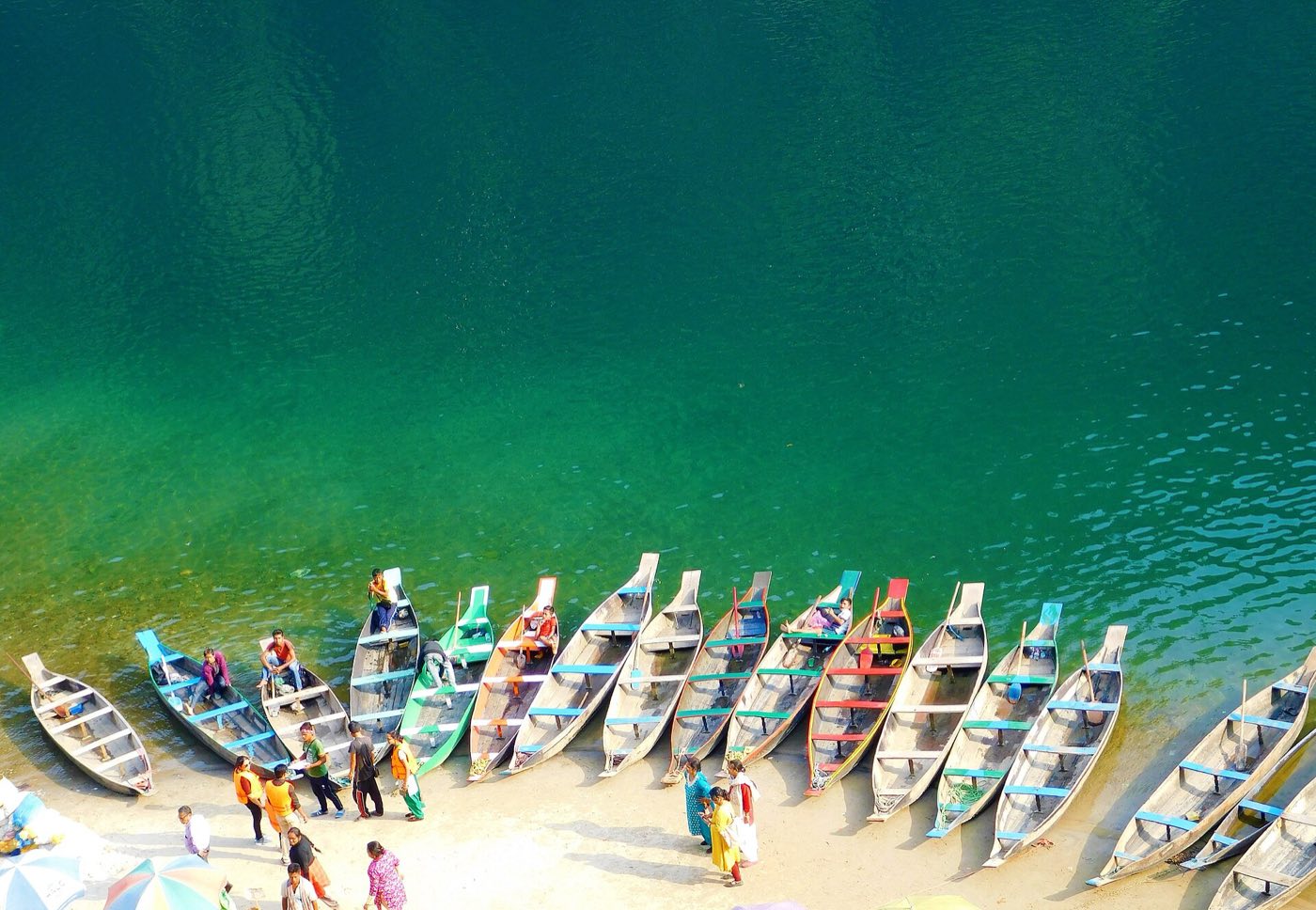 Colourful wooden boats lined up on the clear green Umngot river at Dawki