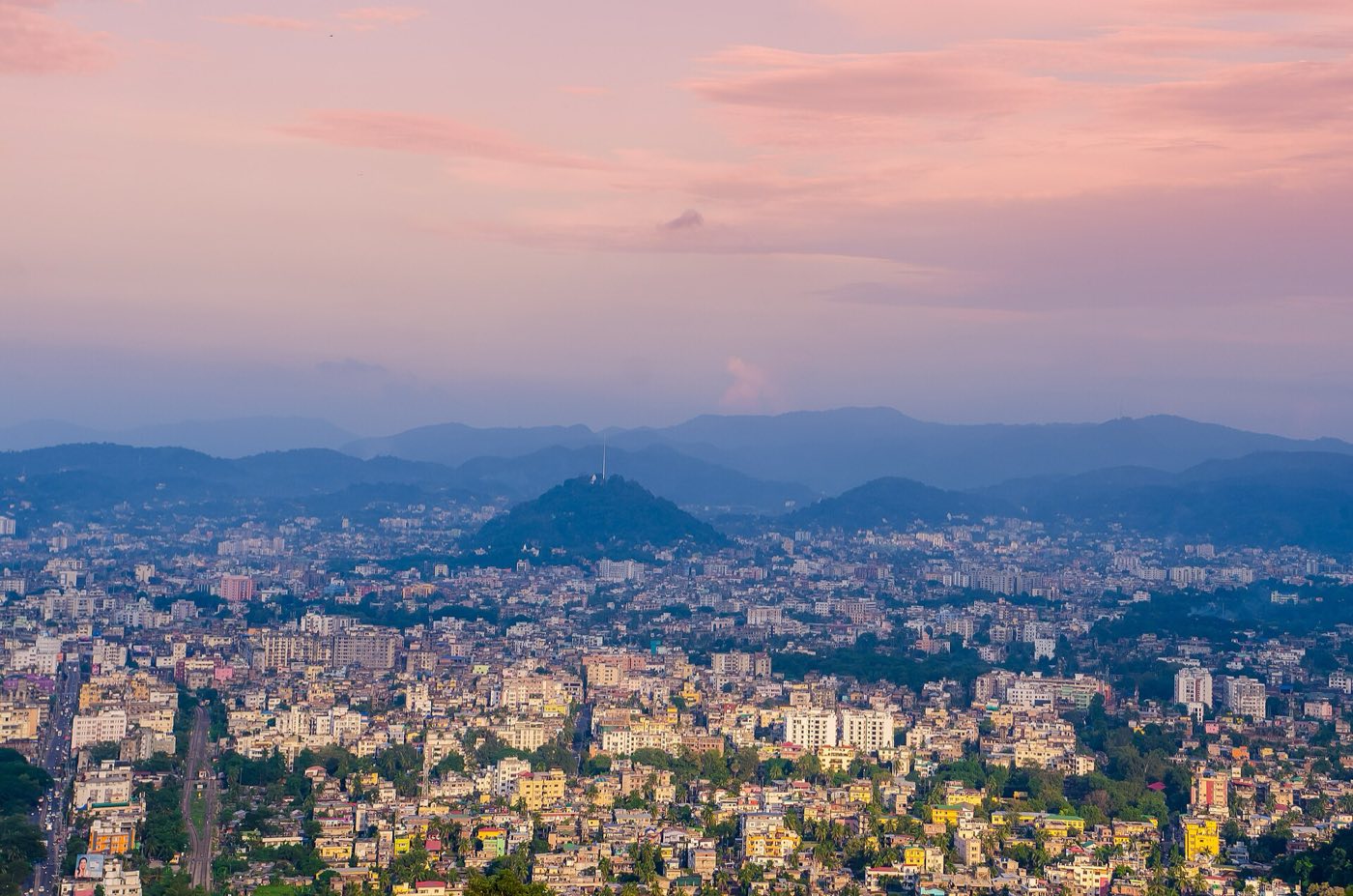 Guwahati city spread below Nilachal hill at dusk, with hills on the horizon