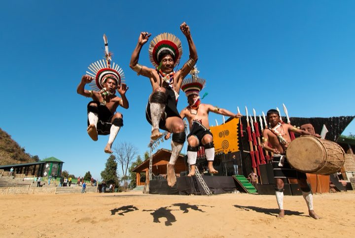 Naga dancers in feathered headgear leaping mid-air at the Hornbill Festival