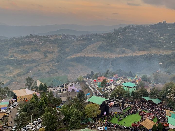 Crowds around the main arena stage at Kisama during the Hornbill Festival, with terraced hills behind