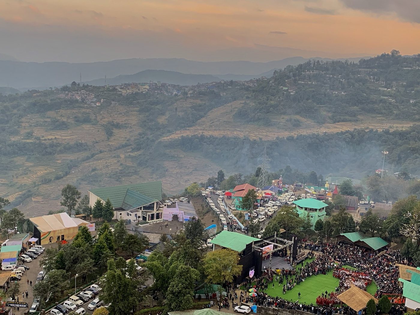 Crowds around the main arena stage at Kisama during the Hornbill Festival, with terraced hills behind